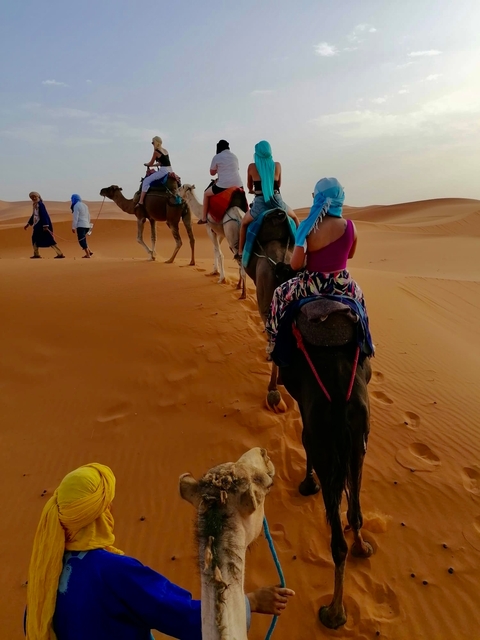 People riding camels through the desert.
