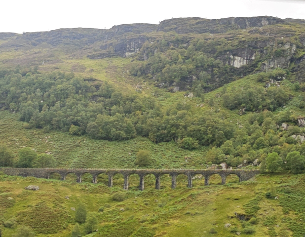 A scenic view of a viaduct surrounded by lush green hills.