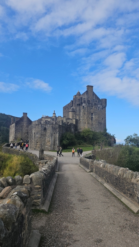 A historic castle with people walking on a path in front.