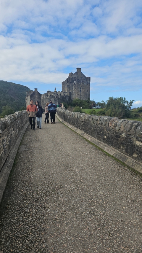 People walking across a stone bridge to a castle