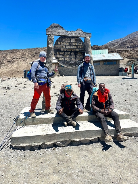 Group of people posing in front of a building on a mountain trek.
