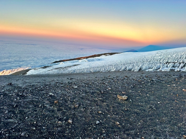 Snow and ice on a mountain slope during sunset.