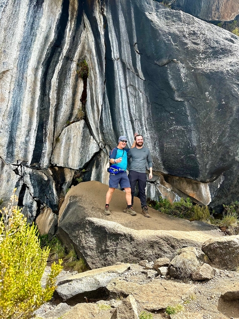 Two people posing in front of striped cliffs.