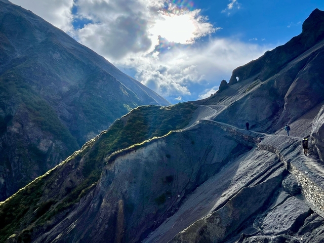 Hilly landscape with trekking paths under a partly cloudy sky.
