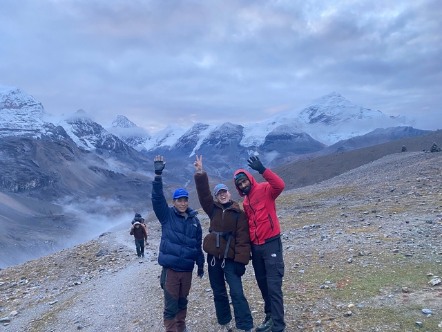 Three people posing cheerfully on a snowy mountain path.