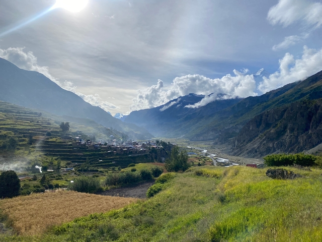 A beautiful landscape of mountains with terraced fields and a village in the distance.