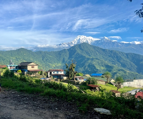 Houses in a hilly landscape with snow-capped peaks.
