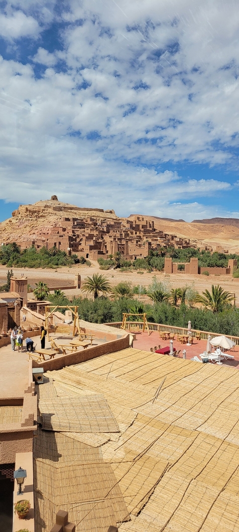 Panoramic view of a historical village with gardens and desert landscape.