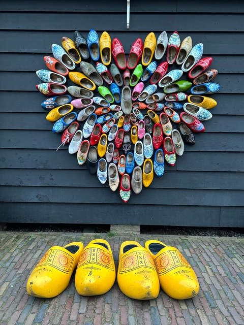 Decorative display of various colored wooden clogs on a wall.