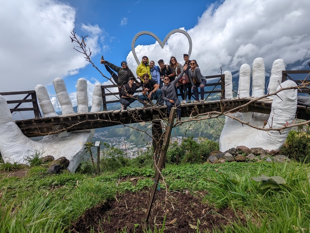 Group of people on a bridge with large hands sculpture.