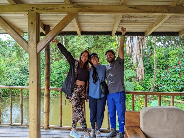 Group of three people on a wooden platform surrounded by greenery.