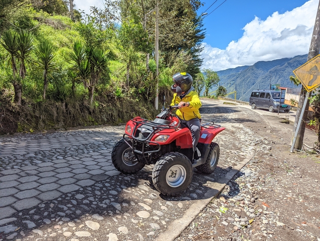 Person riding an ATV on a mountain road.