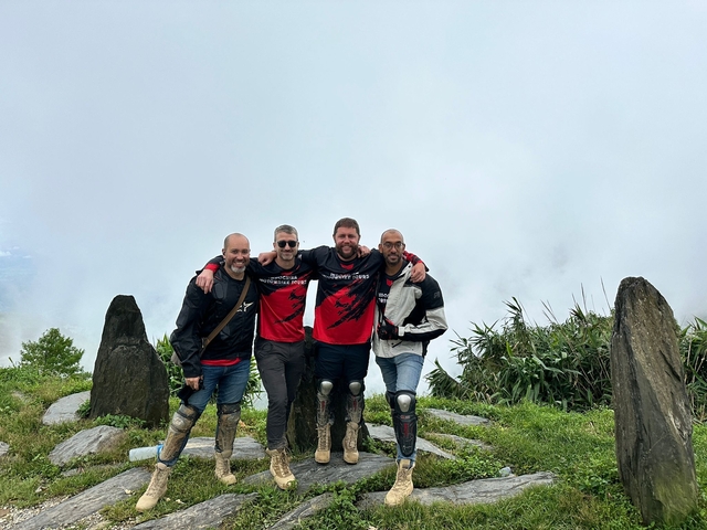 Four friends posing on a misty mountain.
