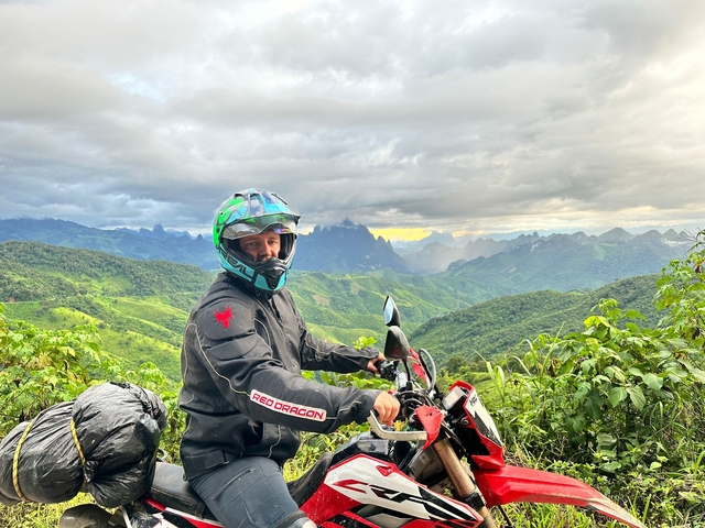 Man on a motorbike with a scenic mountain view.