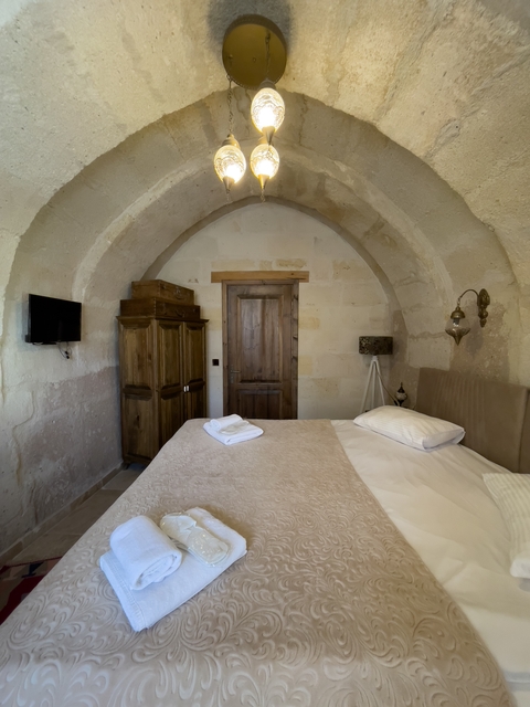A cozy bedroom with arch ceiling and wooden furniture.