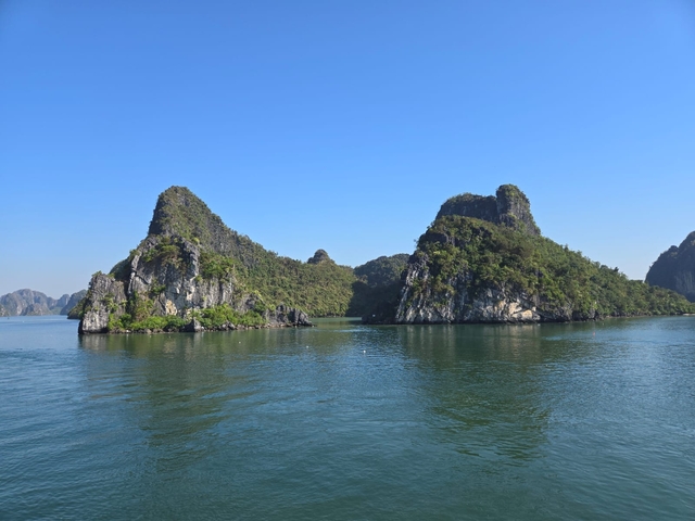 Limestone islands covered with greenery in clear blue water.