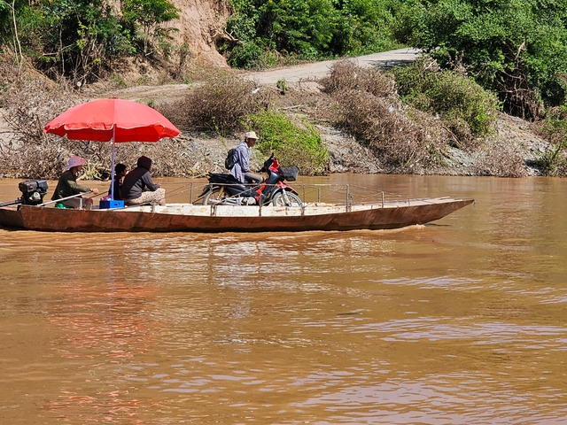 People on a small boat with a bicycle, traveling along a river.