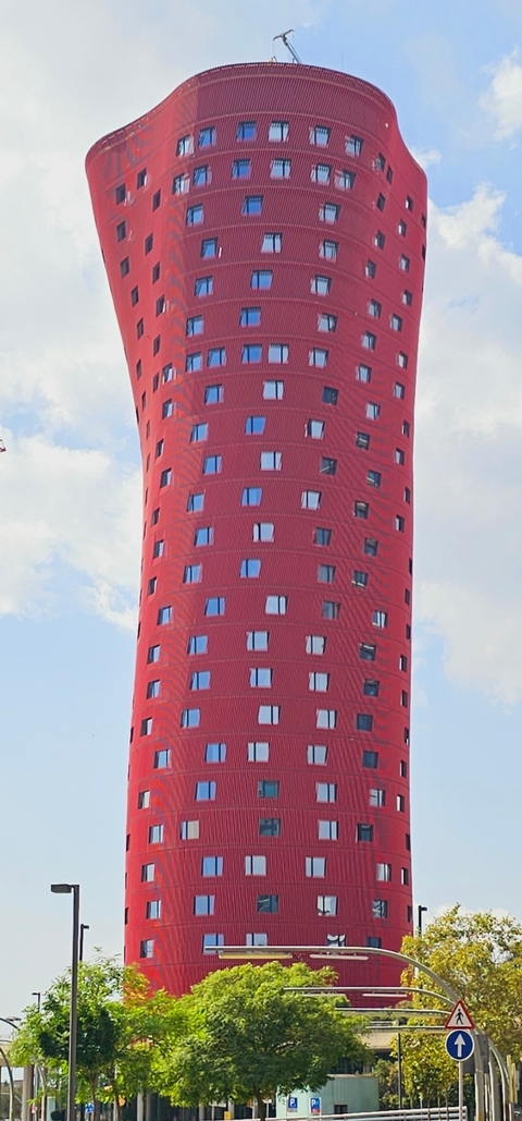Part of a modern red skyscraper against the sky.