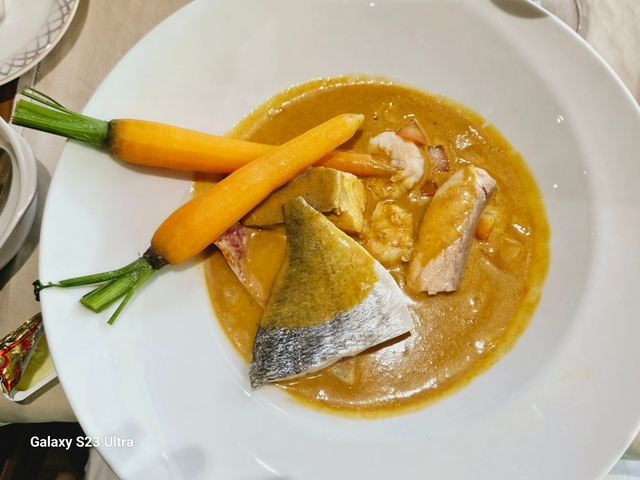 A dish with carrots and fish in sauce.