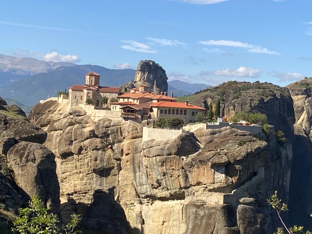Monastery built on a cliff in a mountainous landscape.