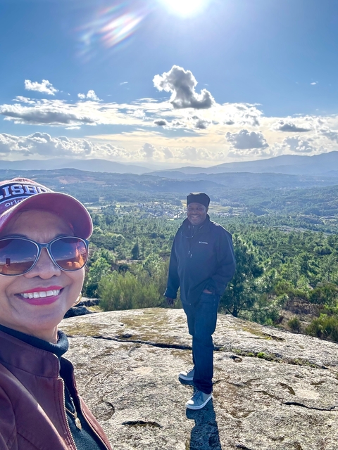 Couple standing in front of a scenic view with hills.