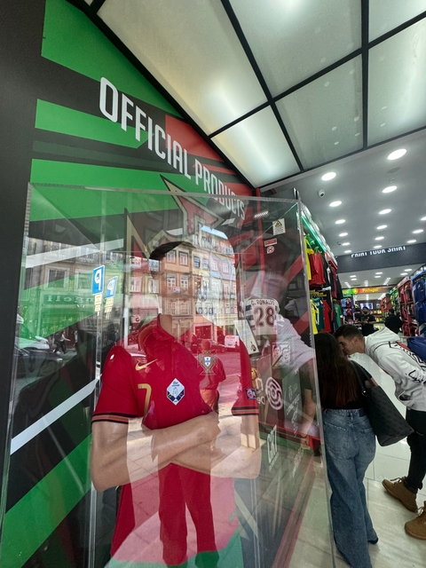 Reflection of building in a shop window with flags and people.