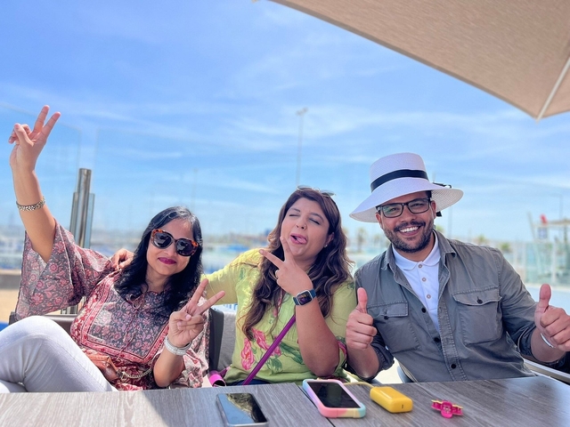 Three people posing with cheerful expressions under an umbrella.