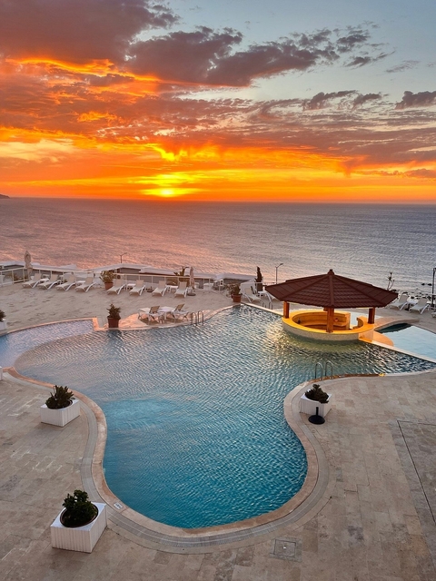 Infinity pool overlooking the ocean with a sunset view.