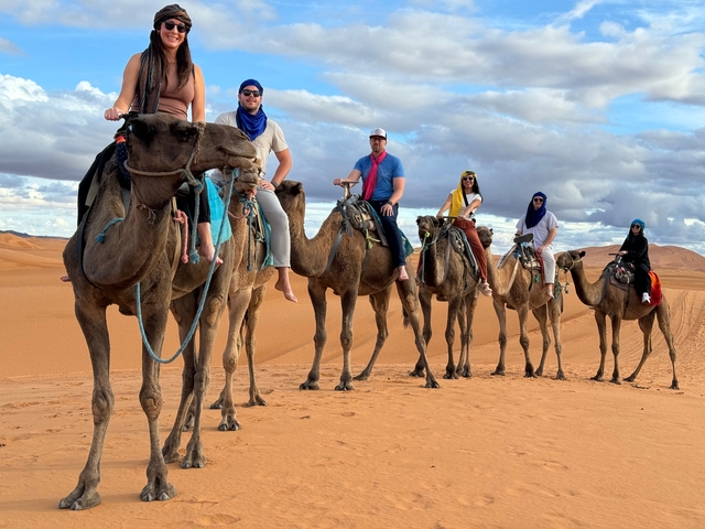 Group of people riding camels in the desert.