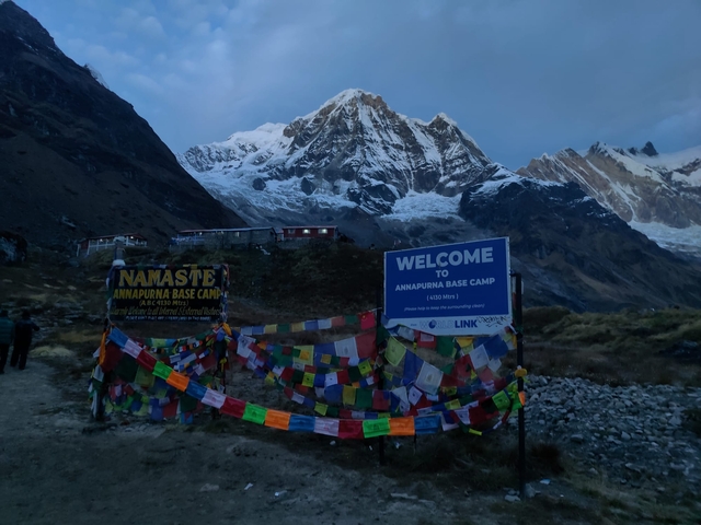 Annapurna Base Camp sign with mountains in the background.