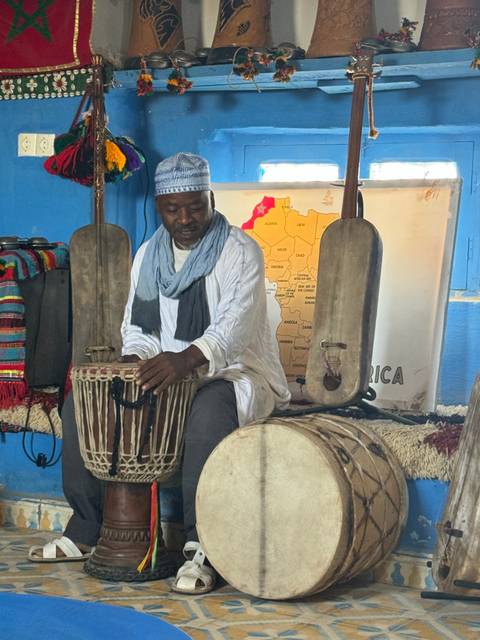 Musician playing a drum in front of a large map.