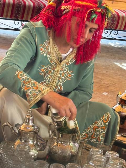 Person in traditional attire pouring tea.