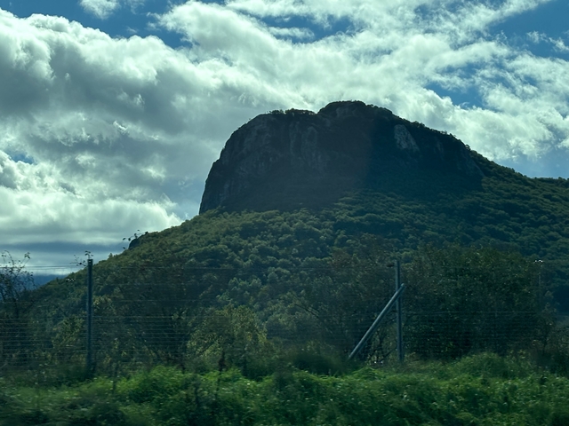 Mountain with lush greenery under a cloudy sky.