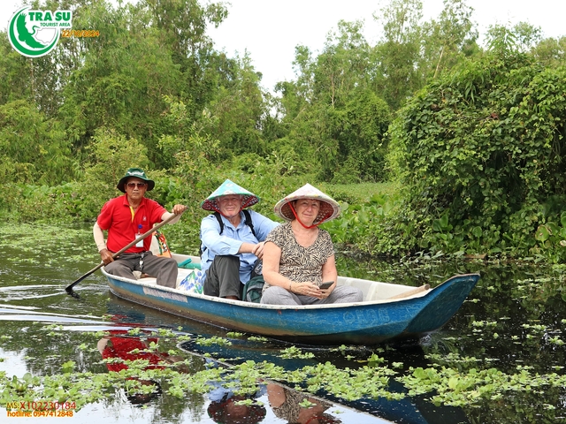 Tourists on a boat in a lush waterway.