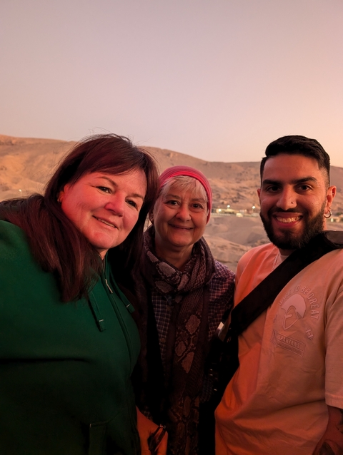 Three people posing with a scenic backdrop.