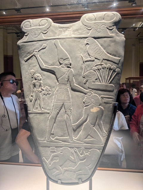 People viewing an ancient carving on display.