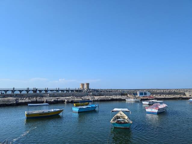 Boats in a harbor with clear blue sky.