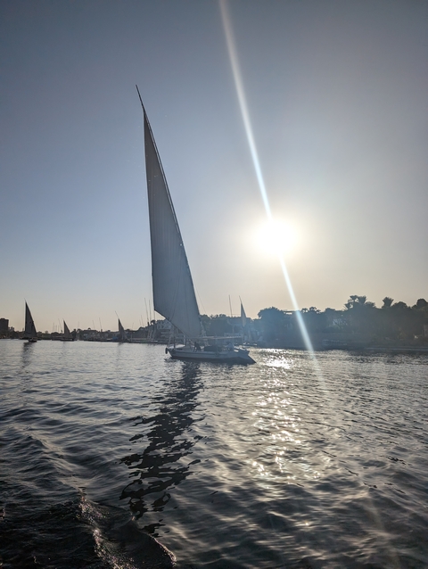 Sailboat on a river with the sun shining.
