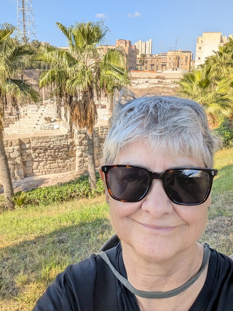 Person in sunglasses with ruins in the background.