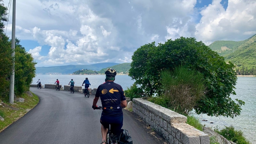 Cyclists on a coastal road with a scenic waterfront view.