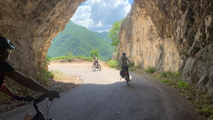 Cyclists riding through a mountainous tunnel.