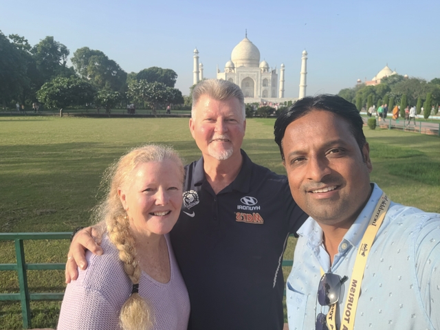 Three people posing in front of the Taj Mahal.