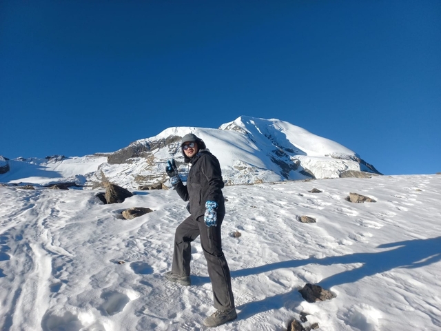 Man trekking on a snowy mountain with clear blue sky.
