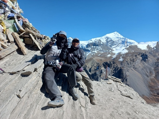 Two trekkers posing with a snowy mountain in the background.