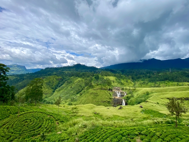 Scenic view with lush greenery and a waterfall in the distance.