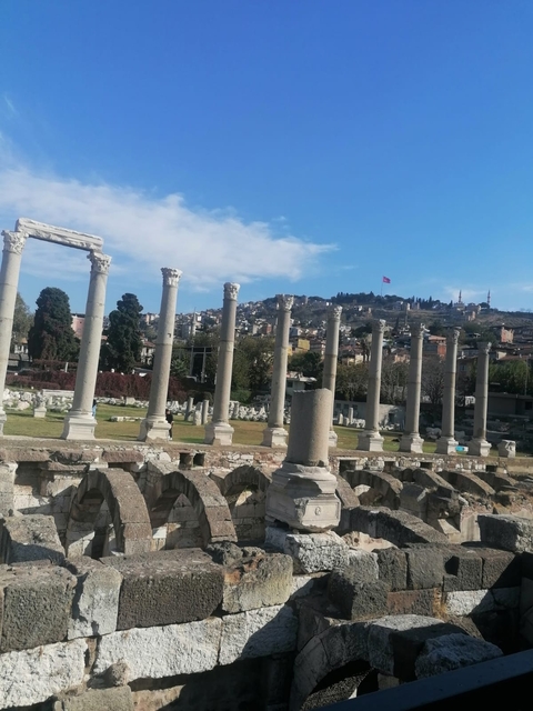 Ruins of an ancient stone marketplace with a distant cityscape.