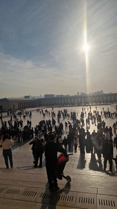 Crowd of people in a large open square with buildings in the distance.