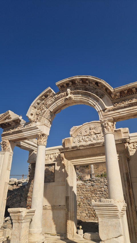 Ancient stone archway with detailed carvings visible against the blue sky.