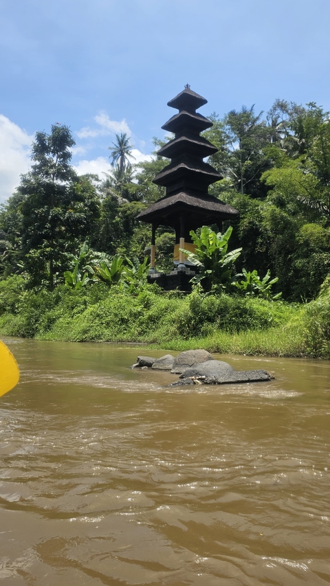 Small shrine by a river surrounded by lush vegetation.