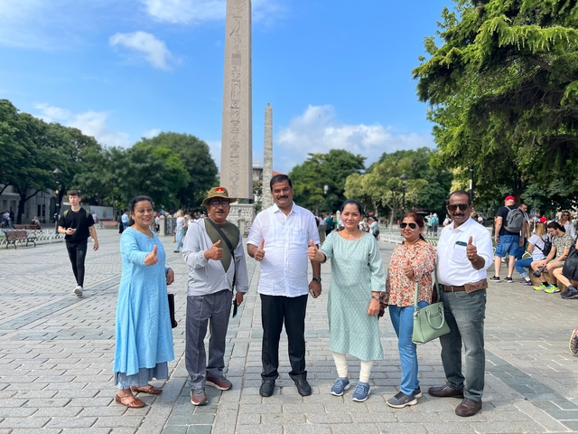 Group of tourists posing in front of obelisks.